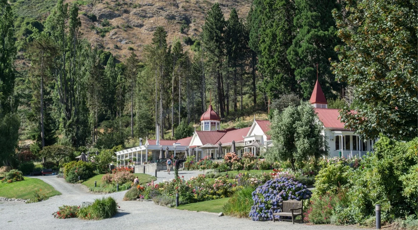 The Colonel's Homestead at Walter Peak High Country Farm, its red roofs and cupolas rising above lakeside rose and hydrangea beds