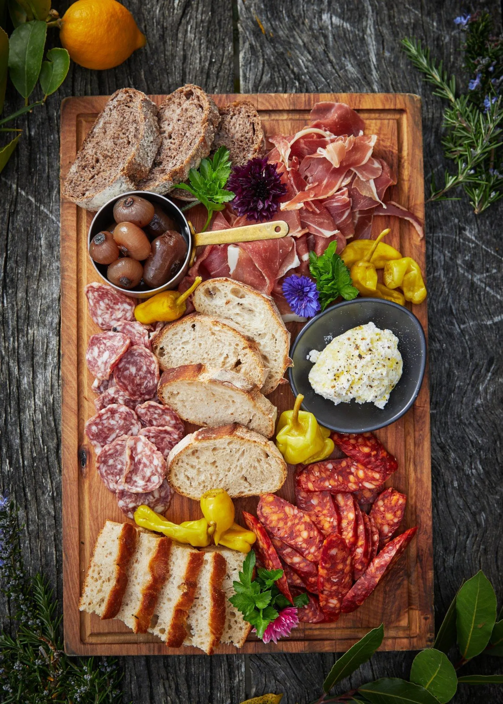 A charcuterie board at Walter Peak with cured meats, blue cheese, walnuts and fresh bread on a dark slate table