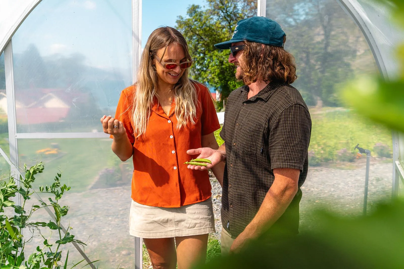 A host and a guest tasting fresh produce inside the polytunnel in the Walter Peak restaurant garden