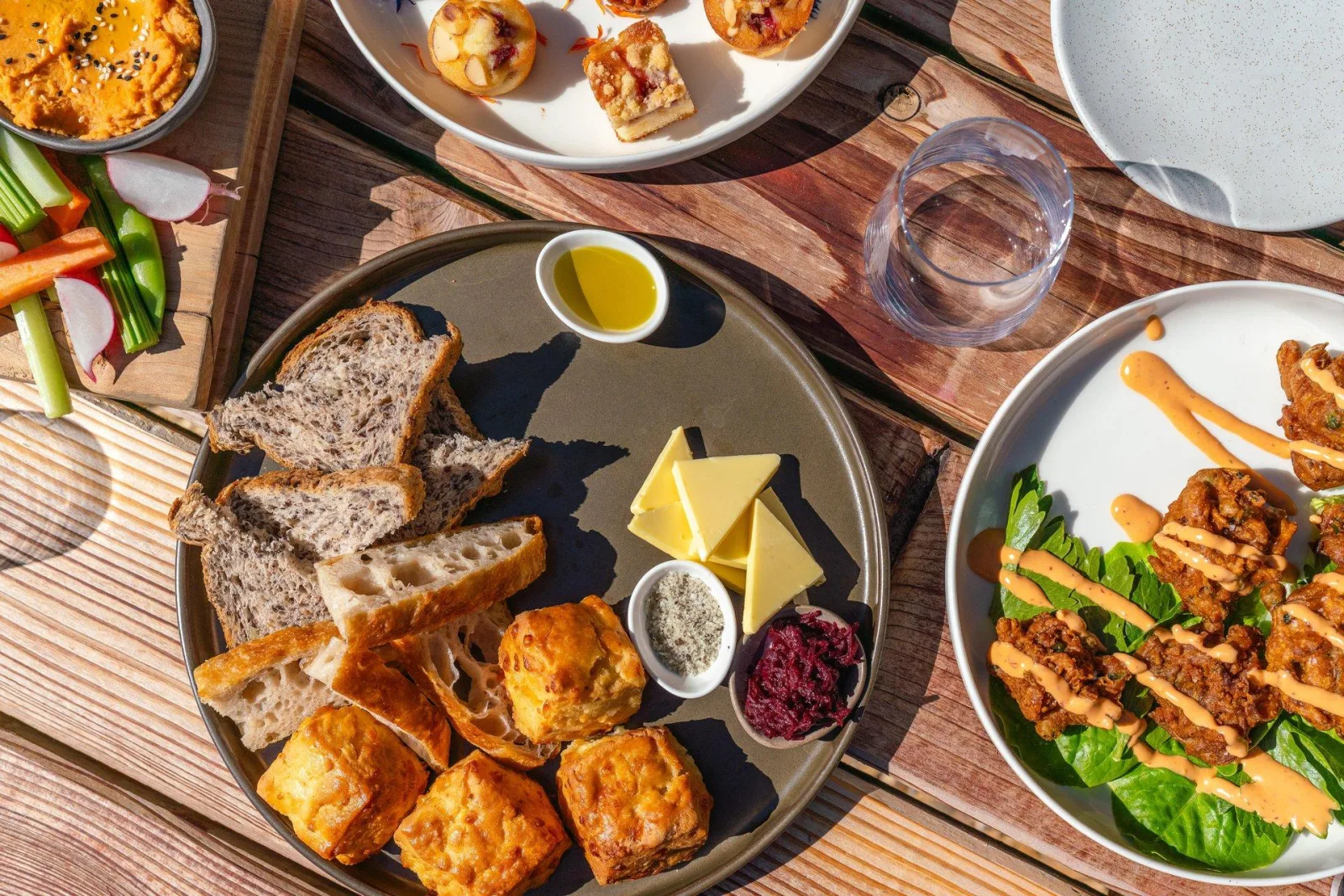 A garden platter of breads, cheeses, dips and grilled vegetables on an outdoor table