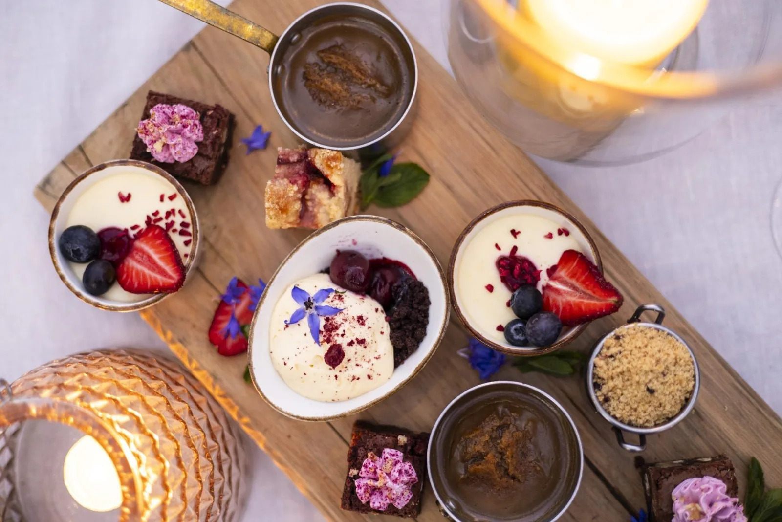 A dessert board of custards, berry slices and cakes on a wooden platter at the homestead